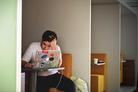 stressed man sitting in a cubicle on his laptop